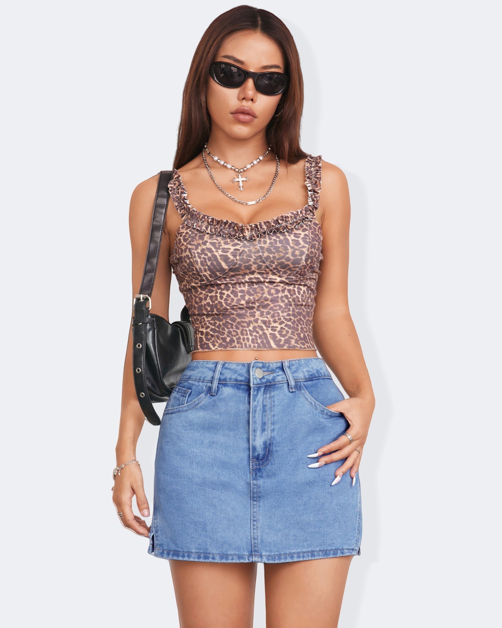 Model wearing a leopard print crop top and denim skort, showcasing trendy summer fashion with sunglasses and a black handbag.